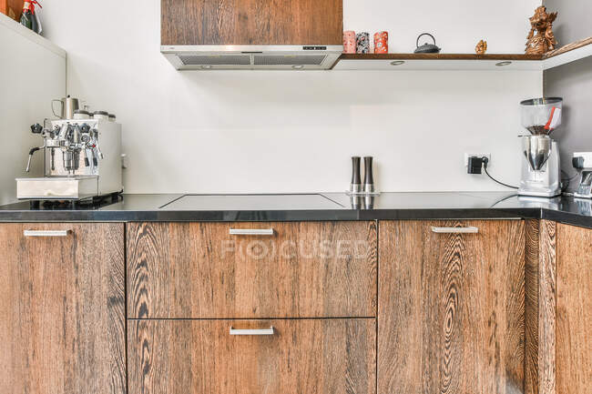 Cocina ligera con textura de madera y diferentes electrodomésticos en apartamento luminoso - foto de stock