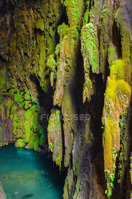 D'en haut à l'intérieur d'une grotte avec un lac en arrière-plan tandis que des gouttes d'eau tombent d'en haut — Photo de stock