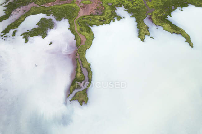 Вид беспилотника на грубые скалистые коричневые образования, окруженные пышными зелеными растениями, покрытыми густым туманом в природе Исландии — стоковое фото
