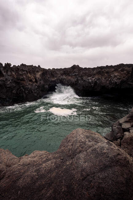 Scenery view of Hervideros with fast water flow among dry mountains under cloudy sky in Yaiza Lanzarote Canary Islands Spain — Stock Photo