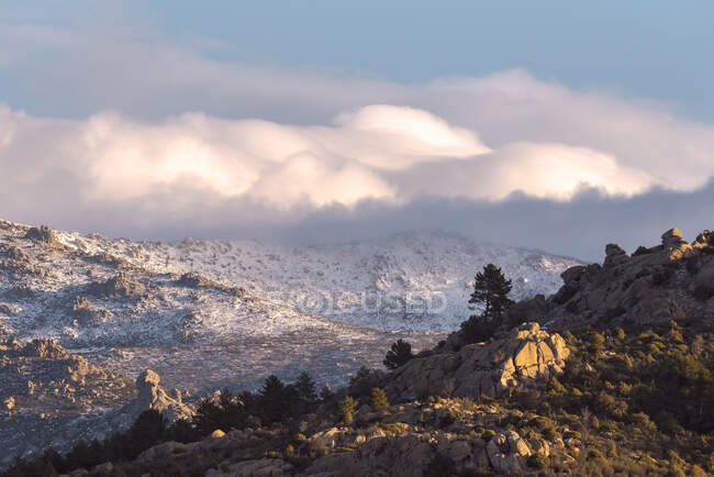Pierres brutes recouvertes de mousse et d'arbustes situées au sommet d'une montagne enneigée dans le parc national de la Sierra de Guadarrama à Madrid, Espagne — Photo de stock