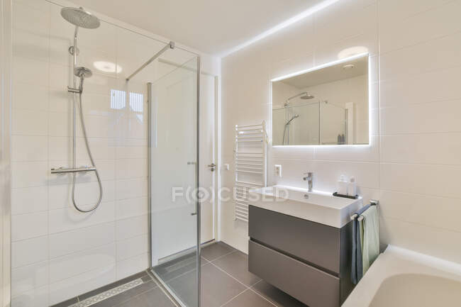 Évier et toilettes situés près de la baignoire derrière un mur de verre dans des toilettes légères à la maison — Photo de stock