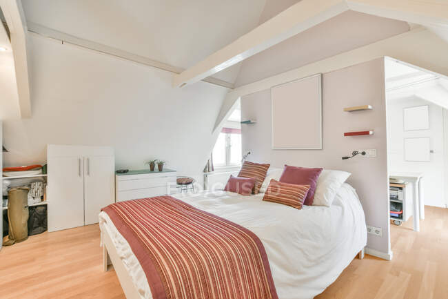 Cama macia confortável com linho branco e travesseiros coloridos no quarto elegante no apartamento moderno — Fotografia de Stock