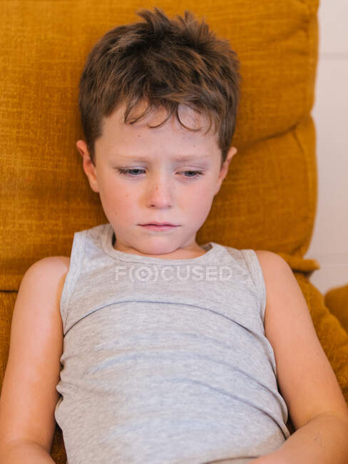Ângulo alto de criança doente infeliz tendo frio e deitado na cama em casa — Fotografia de Stock