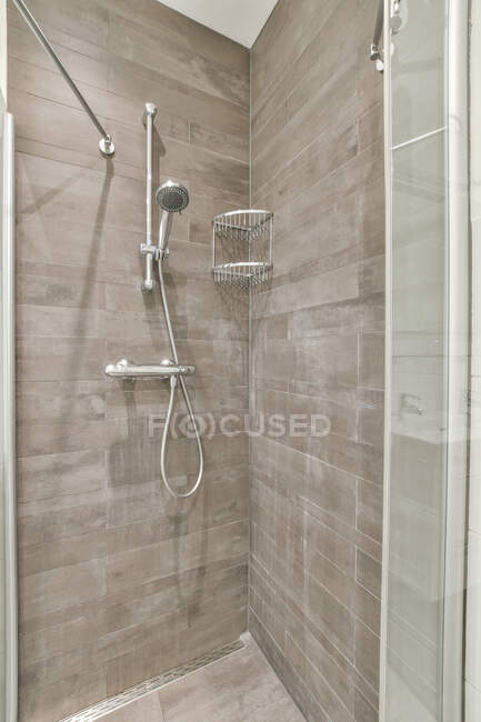 Torneira e prateleira metálica penduradas nas paredes de azulejos no canto da cabine do chuveiro no banheiro — Fotografia de Stock