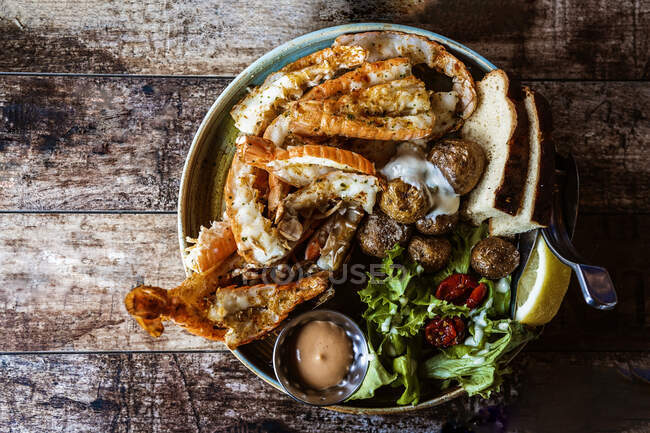 Table en bois avec plat typiquement islandais aux crevettes royales et pain au restaurant à la lumière du jour — Photo de stock