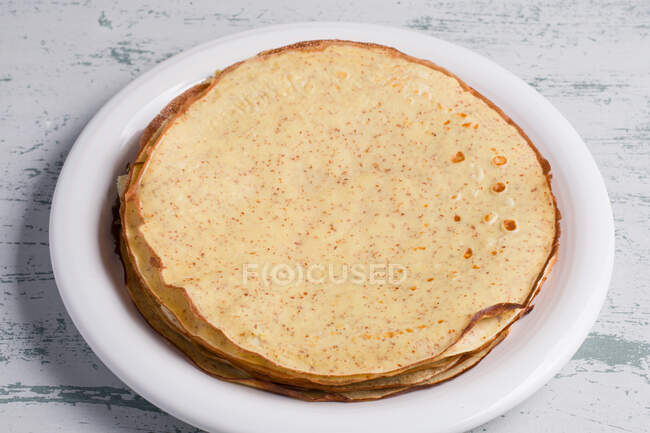 From above heap of healthy delicious round keto crepes with erythritol sweetener served on plate on table in light kitchen — Stock Photo