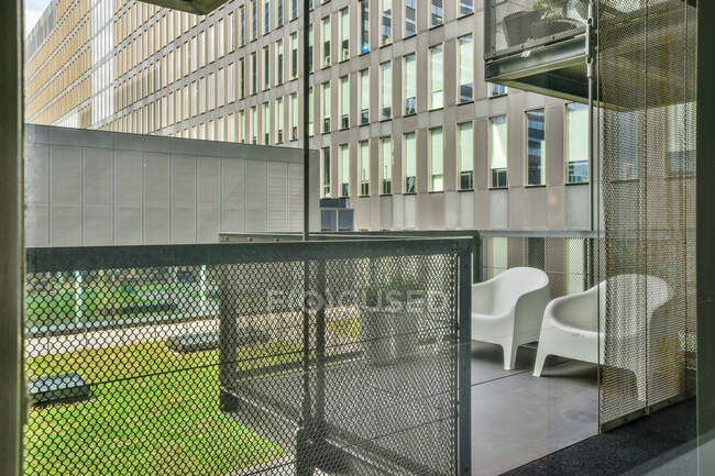 Sillones en la terraza contra el exterior de la casa contemporánea de varios pisos y césped durante el día en Ámsterdam Países Bajos - foto de stock