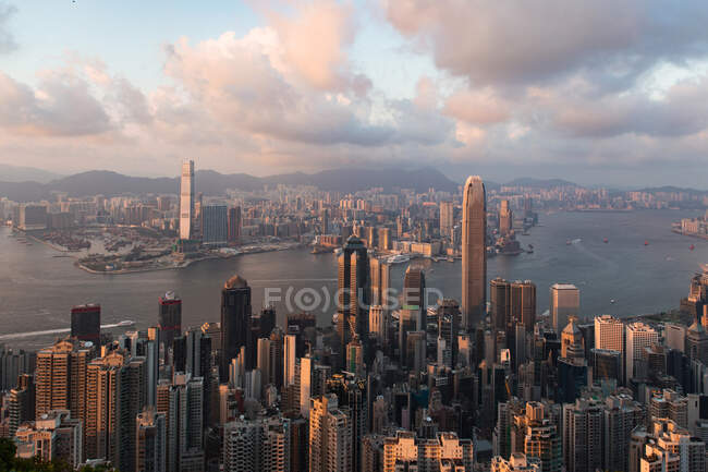 Espectacular paisaje de río que fluye a través del distrito con varios rascacielos modernos contra el cielo nublado del atardecer en Hong Kong - foto de stock