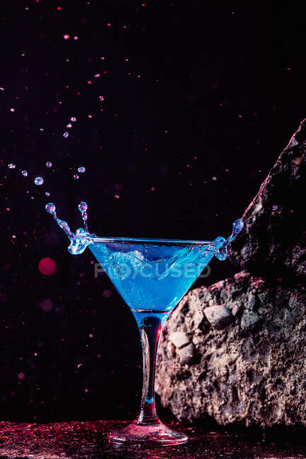 Cóctel Blue Lagoon en cristal elegante colocado sobre superficie rugosa sobre fondo negro - foto de stock