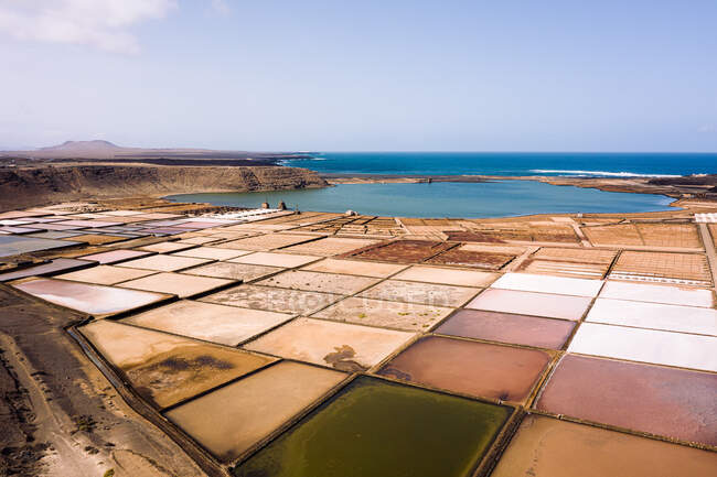 From above salinas de Janubio against mounts and sea with horizon under cloudy sky in Yaiza Lanzarote Canary Islands Spain — Stock Photo