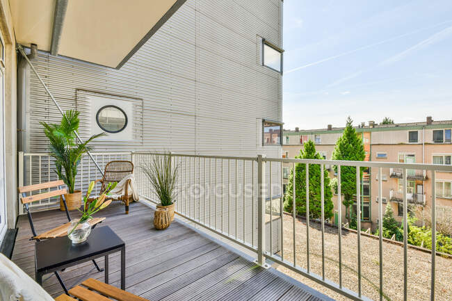 Ampia terrazza in legno con comode sedie e piante in vaso in un moderno condominio — Foto stock
