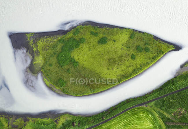 Вид беспилотника на грубые скалистые коричневые образования, окруженные пышными зелеными растениями, покрытыми густым туманом в природе Исландии — стоковое фото