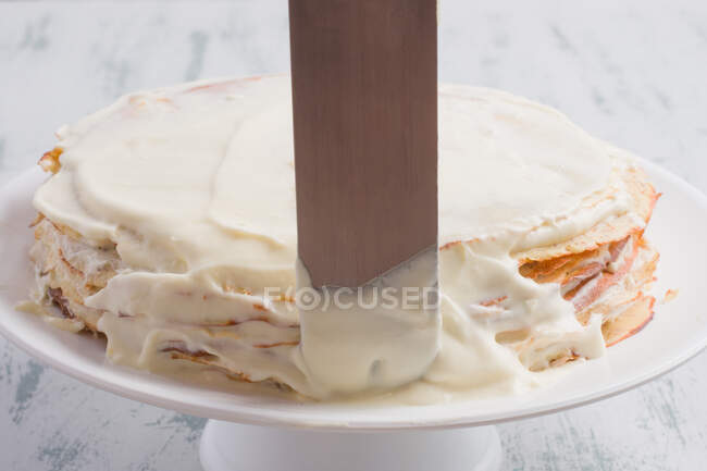 Metal spatula on keto crepe cake with erythritol sweetener and frosting made of cream cheese and whipped cream served on table — Stock Photo