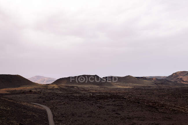 Ruta áspera entre volcanes en el Parque Natural de Timanfaya en Lanzarote España - foto de stock