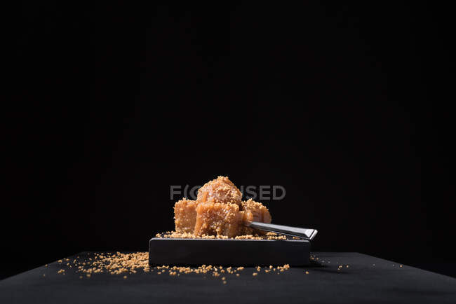 Gourmet quince jelly paste in ceramic plate sprinkled with sesame seeds on black background — Stock Photo
