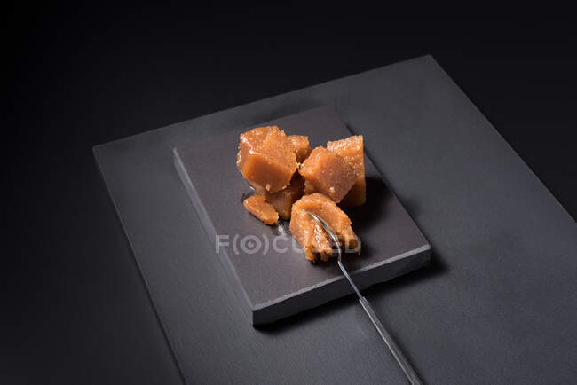 From above gourmet quince jelly paste in ceramic plate on black background with spoon — Stock Photo