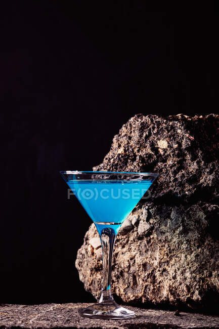 Cocktail Blue Lagoon in cristallo elegante disposto su superficie ruvida su fondo nero — Foto stock