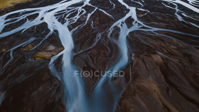 Vista aérea pitoresca de rios curvilíneos que fluem através de terrenos montanhosos selvagens na Islândia — Fotografia de Stock
