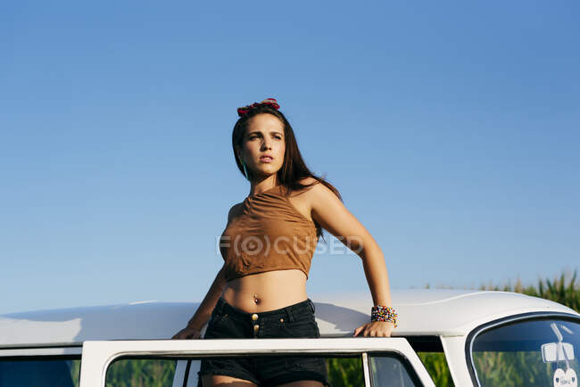 Красивая уверенная брюнетка, стоящая в фургоне в солнечный день — стоковое фото