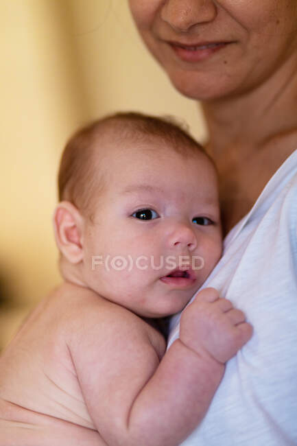 Vista lateral da cultura calma jovem mulher abraçando e acariciando bebê adorável durante o dia — Fotografia de Stock