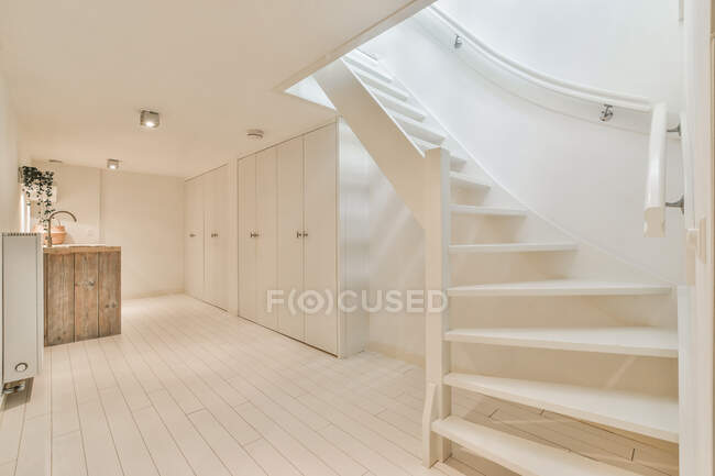 Design creativo della scala ondulata contro lavabo e armadi a pavimento sotto le lampade a casa — Foto stock