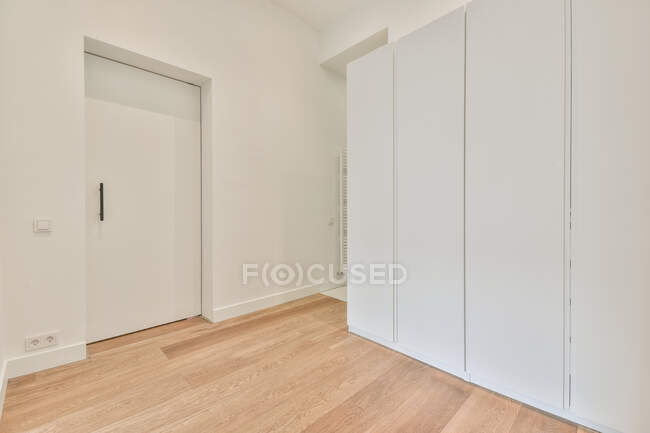 Интерьер современной просторной спальни с белым шкафом расположен рядом с дверью — стоковое фото