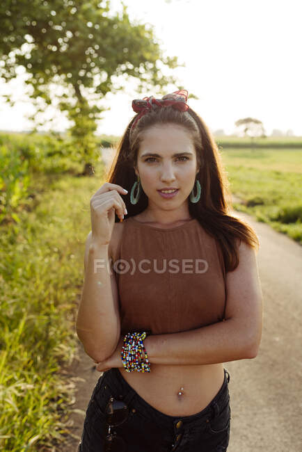 Beautiful brunette girl in summer clothes standing on the road looking at the camera — Stock Photo