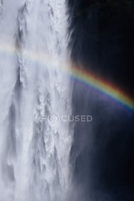 Atemberaubende Regenbogenkulisse über dem schnellen, mächtigen Skogafoss-Wasserfall, der durch eine Felsklippe in Island fließt — Stockfoto