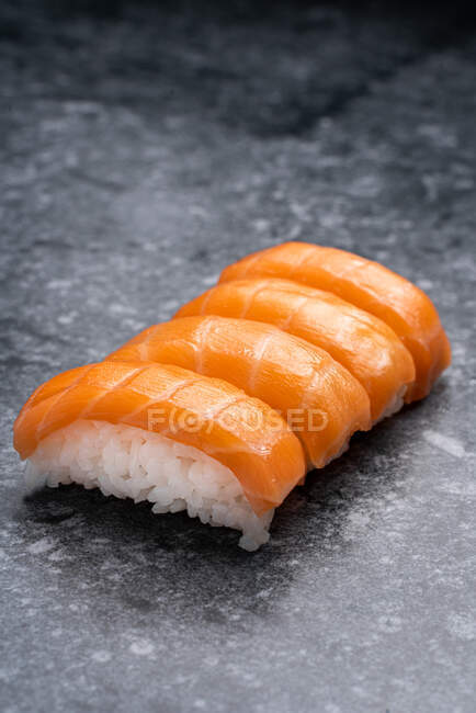 Набор подобных вкусных традиционных японских суши с белым рисом и свежим лососем подается на мраморном столе в светлом помещении — стоковое фото