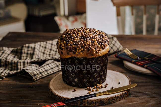 Sweet homemade baked panettone on round wooden stand near knife for celebrating Christmas — Stock Photo
