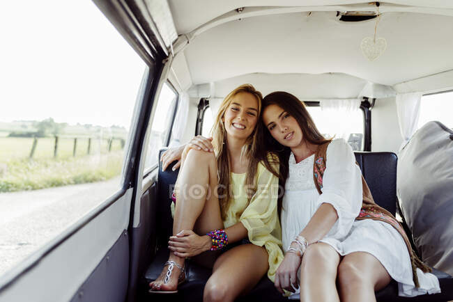 Chicas en un viaje en una zona rural sentadas dentro de una camioneta mientras miran a la cámara - foto de stock