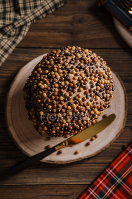 From above of sweet homemade baked panettone on round wooden stand near knife for celebrating Christmas — Stock Photo