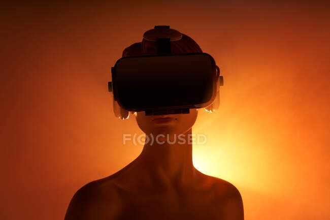 Frauenattrappe mit VR-Brille vor leuchtend orangefarbenem Hintergrund als Symbol futuristischer Technologie — Stockfoto