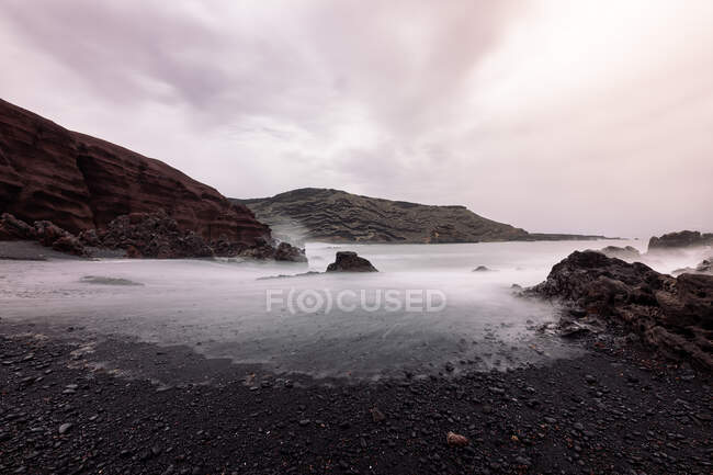 Ciclos Beach against misty sea and Guincho Volcano under cloudy sky in Golfo Yaiza Lanzarote Canary Islands Spain — Stock Photo