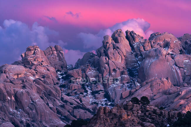 Жорсткі камені, вкриті мохом і чагарниками, розташовані на вершині засніженої гори в Національному парку Сьєрра - де - Гуадаррама в Мадриді (Іспанія) під час заходу сонця. — стокове фото