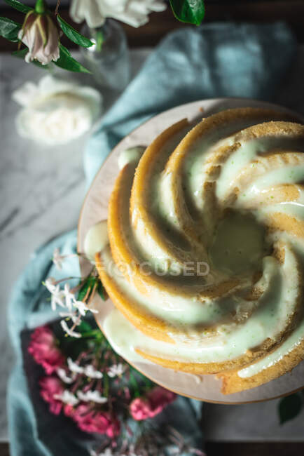 Vista superior del delicioso pastel de esponja de lima servido en un plato blanco cerca de flores y rodajas de lima - foto de stock