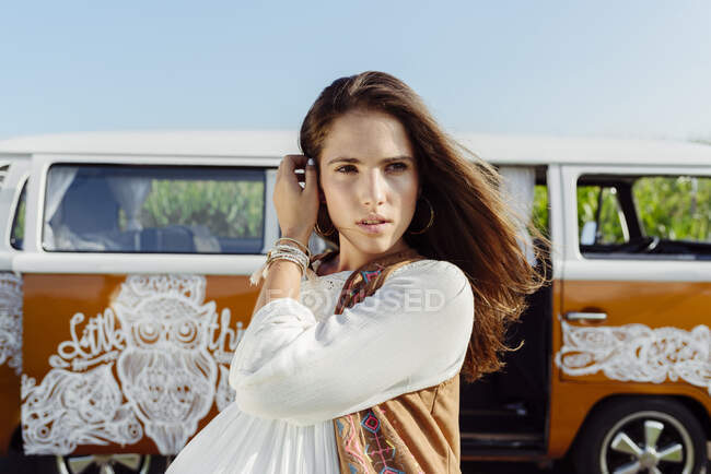 Schöne brünette Mädchen in Sommerkleidung vor einem Lieferwagen stehen und in die Kamera schauen — Stockfoto