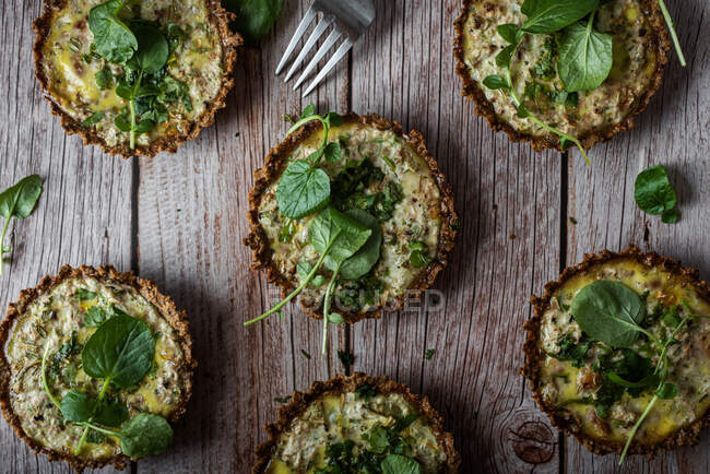Top view of cauliflower and walnut cakes with greens near fork on planked wooden table — Stock Photo