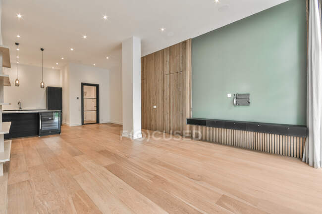 Интерьер просторной кухни с минималистской черной мебелью в современной квартире с белыми стенами, деревянным паркетом и колоннами — стоковое фото