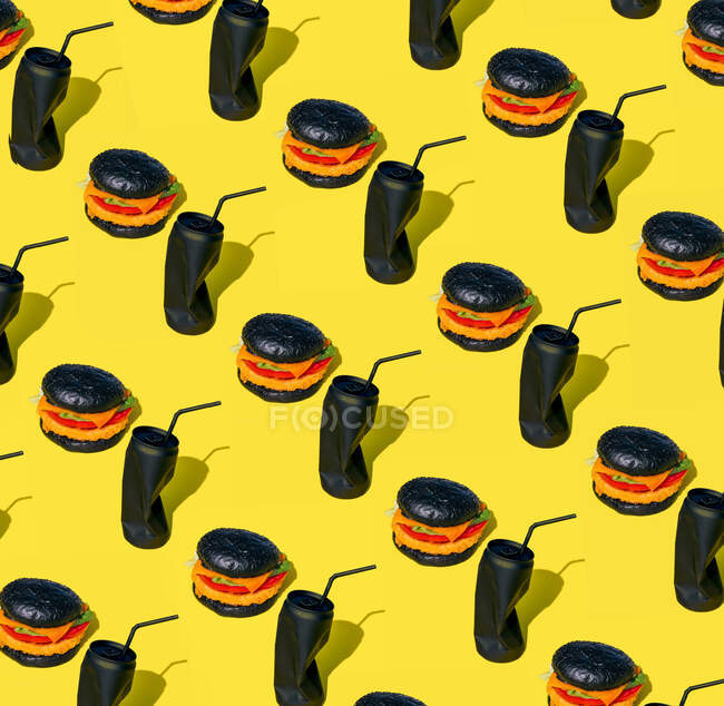 Fundo de hambúrgueres frescos com legumes colocados perto de latas pretas de refrigerante com palha contra fundo amarelo — Fotografia de Stock