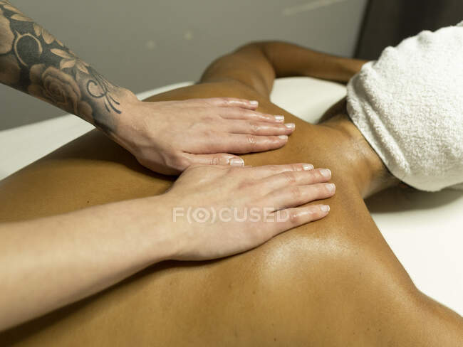 From above unrecognizable female masseur massaging back of client in towel on couch in light spa center — Stock Photo