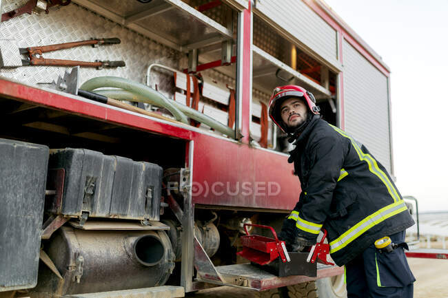 Fire truck with all the tools in sight and fireman with his hands inside a tool box — Stock Photo