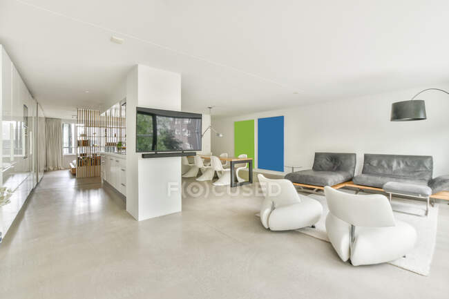 Moderno salón interior con sillones y sofá en la alfombra contra la televisión y la mesa en casa - foto de stock