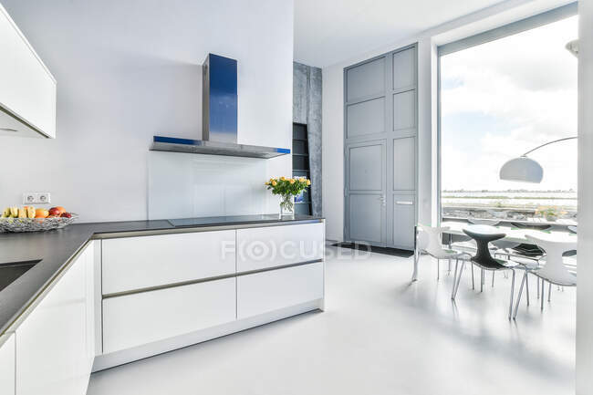 Design creativo di cucina e sala da pranzo con lampada e tavolo contro finestra in casa luce — Foto stock