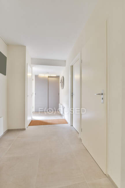 Intérieur de couloir moderne avec radiateur sur mur blanc et tapis contre placard avec lampe dans la maison — Photo de stock