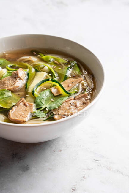 Ciotola di tradizionale vietnamita Pho bo noodle zuppa con foglie di basilico e lime posto sul tavolo di marmo in sala luce — Foto stock