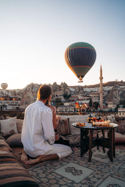 Rückansicht von nicht wiederzuerkennenden liebevollen Mann umarmt Frau beim Dessert essen und Tee trinken zusammen auf der Terrasse — Stockfoto