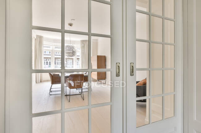 Porta branca fechada que conduz à sala de jantar clara espaçosa com mesa e cadeiras — Fotografia de Stock