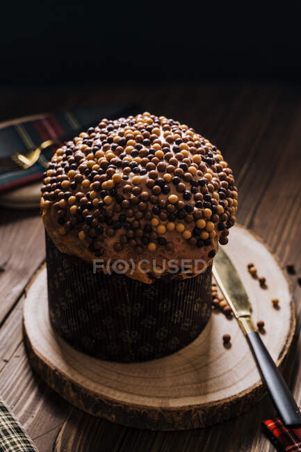 From above of sweet homemade baked panettone on round wooden stand near knife for celebrating Christmas — Stock Photo